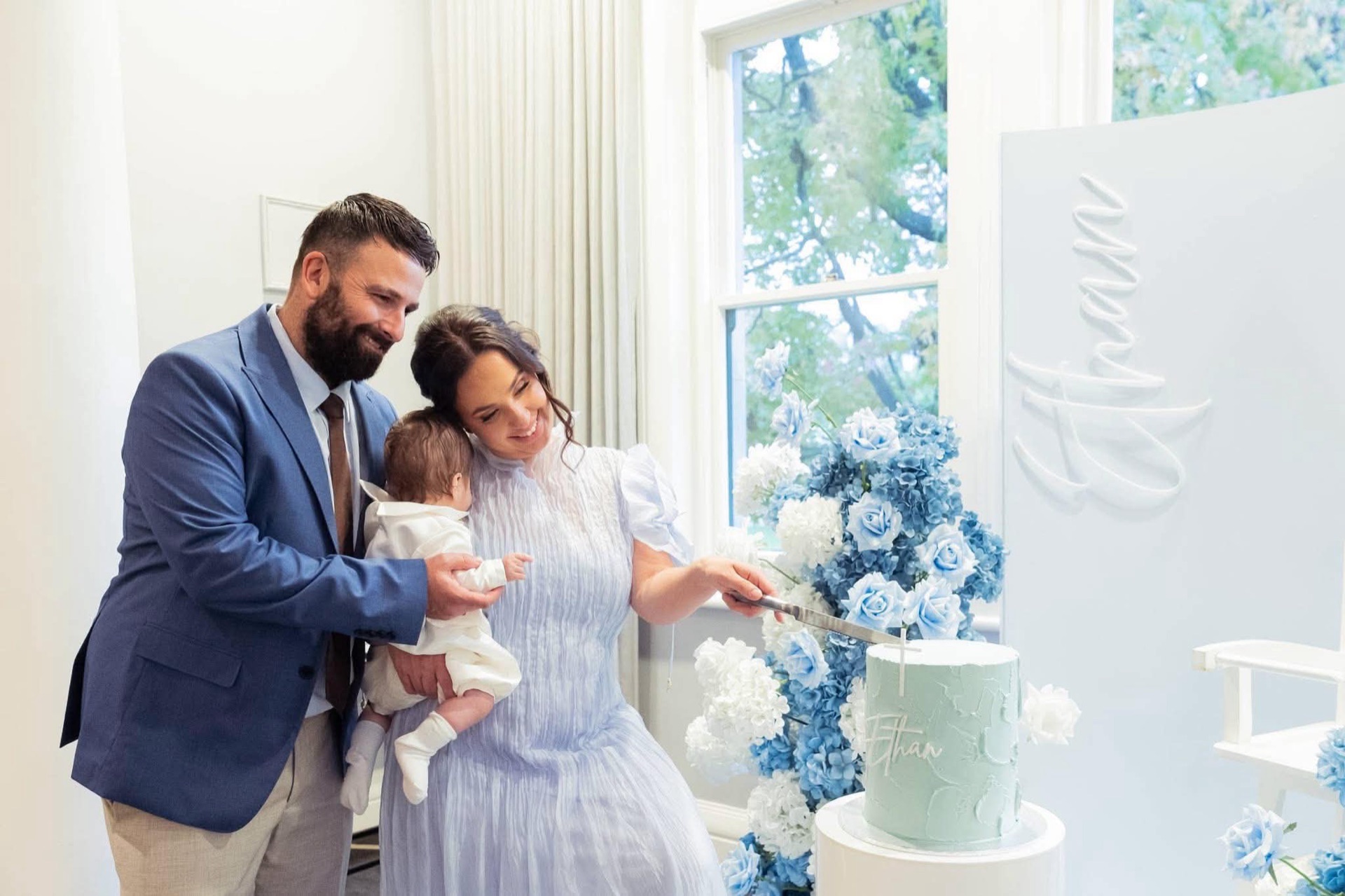 A family gathered around a christening cake photographed by Royale Photography in Melbourne.