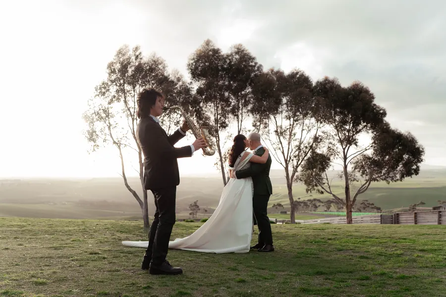 A couple exchange vows in silhouette against an open evening sky