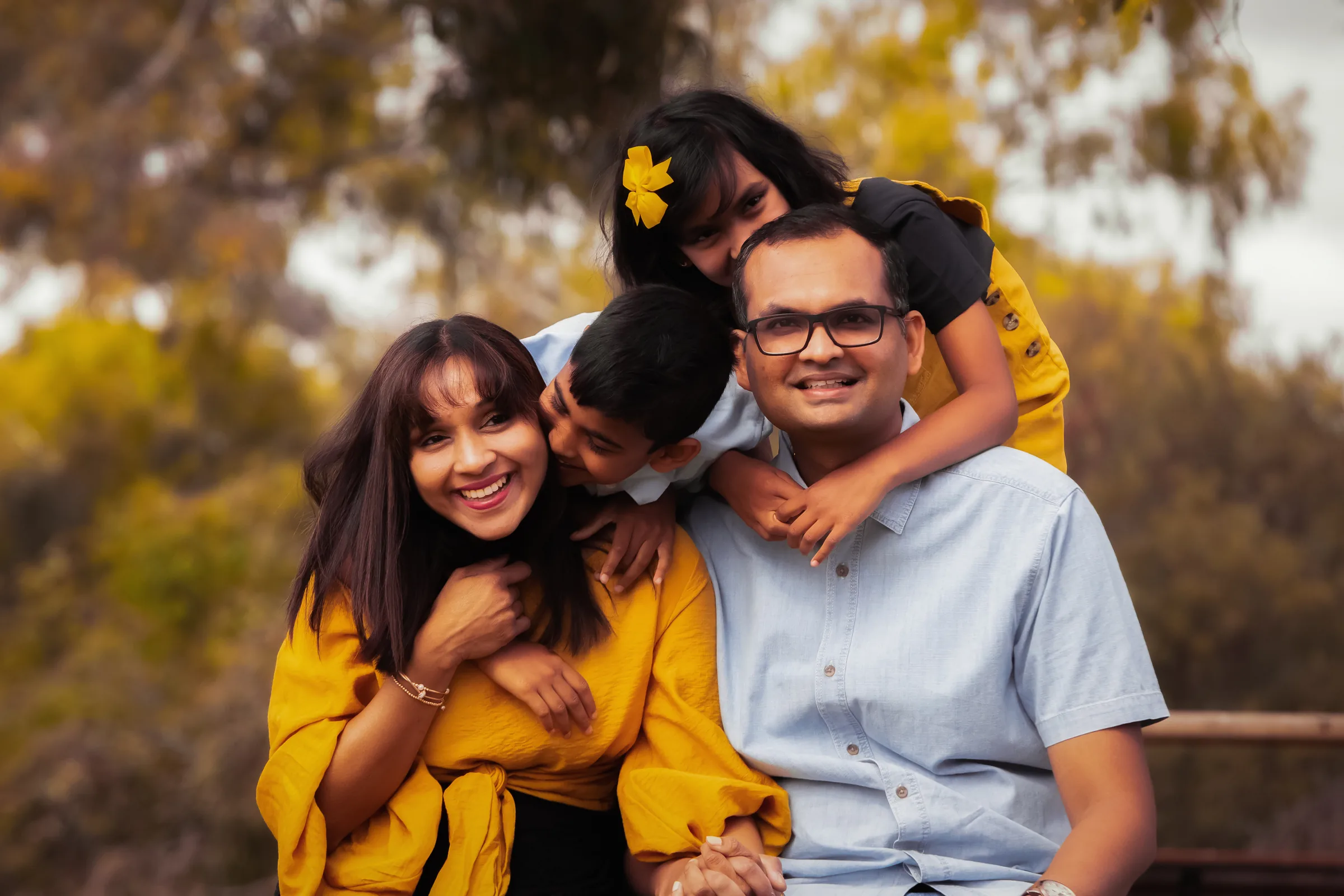 A family laughing together outdoors in warm autumn light, photographed by Royale Photography.